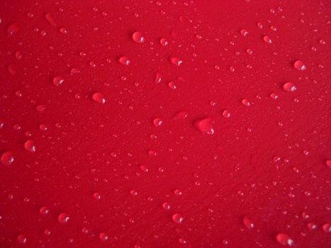 waterdrops distributed on red leathery background