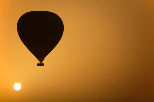 A hot air Balloon backlit by the rays of the morning Sun. 