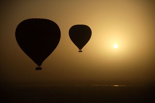 Two hot air balloon silhouettes  in the dry morning of Luxor, Egypt.