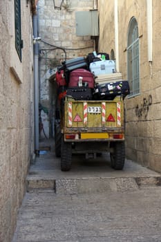 Tractor moving tourist's luggage at narrow Jerusalem streets