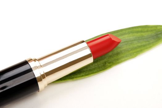 glamor red shiny lipstick and green leaf isolated on white background