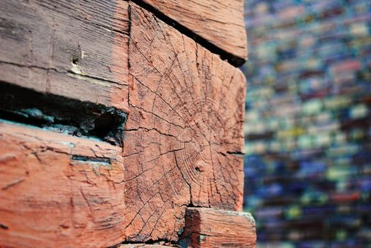 A corner of a wooden wall with brick wall in background.