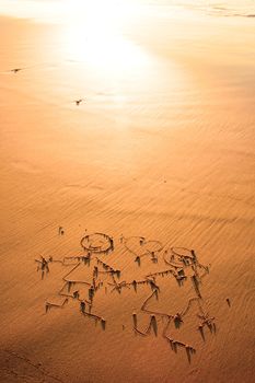 Two children holding hands drawn in the sand on the atlantic coast