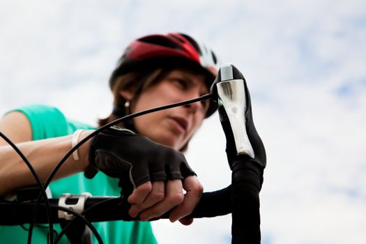 Young woman wearing helmet leaning on a bicycle