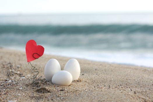 three white easter eggs on the sandy beach