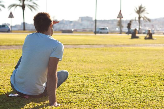 young man sitting on the grass and waiting