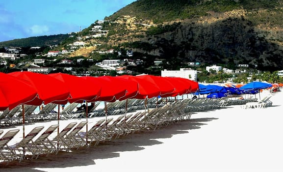 Red and blue parasols with lounge chairs on a beach