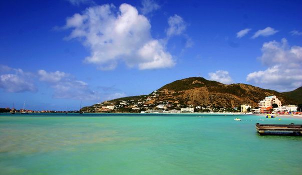 Mountain on St-Martin coastline with green sea.