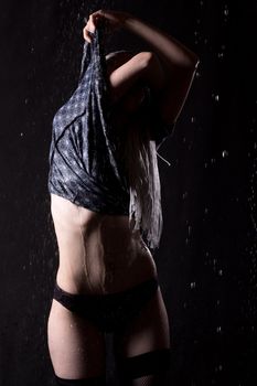 girl undressing in the rain on black background 
