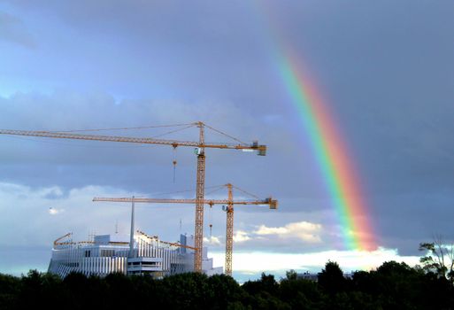 Splash of rainbow covering cranes at construction site