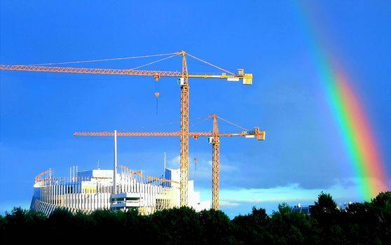 Rainbow over cranes on construction site