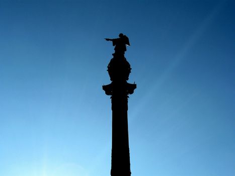 Silhouette of Columbus statue pointing to the Americas