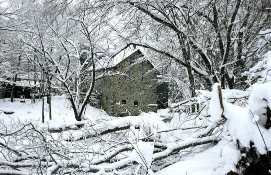 Old mill along a river during a heavy snow fall