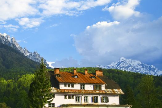 Old rural hotel and Slovenian Alps in the background viewed from Kranjska gora