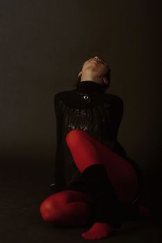 Silhouette of a nice girl in red stocks sitting on a floor