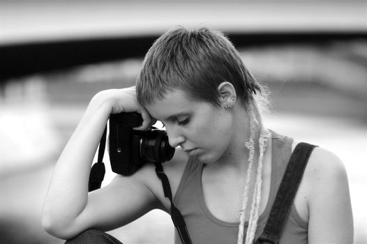 Young sad woman with a short haircut holding camera