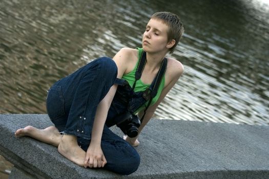 Young pretty girl with the camera resting near the river