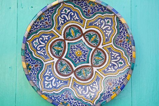 Traditionaly painted ceramic plate displayed at the wooden wall.