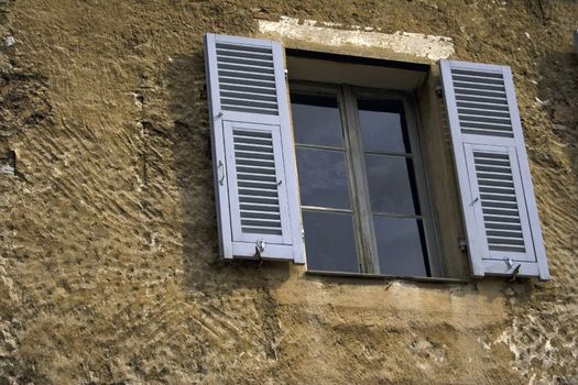 Window with gray shutters in the ancient house 
