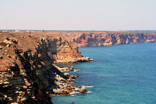 Rocky bent coastline with the visible horizon and the waves breaking