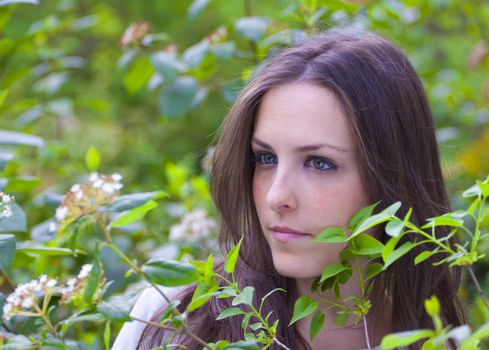 Young attractive woman portraited in the greenery of the city park.