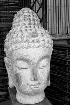 Black and white buda head statue made of stone situated in a garden