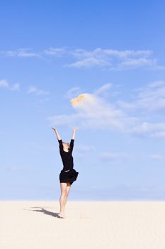 Beautifull girl playing with the sand on the dune.