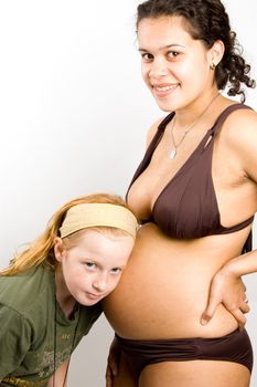little girl is listening to the baby inside the belly on white