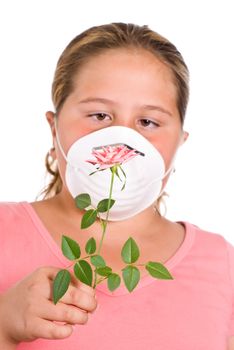 Concept image of a girl with allergies featuring a young girl holding a rose in front of her face while she wears a dust mask