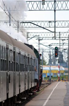 Steam retro train starting from the platform at railway station
