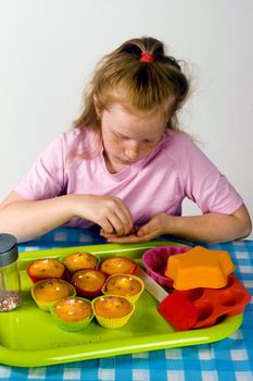 little girl is decorating small cupcakes