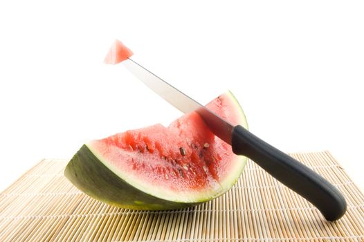slice of a watermelon with a knife with piece of the watermelon on white
