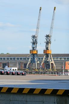 Cranes, new cars on the dock in a harbour
