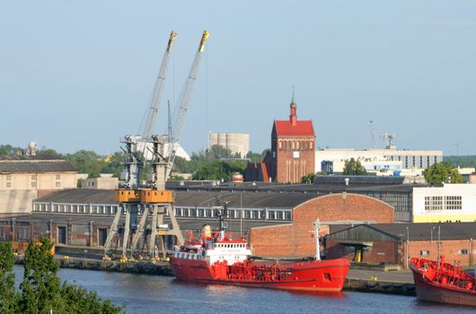 Industrial landscape with two big cranes on the dock and moored ships
