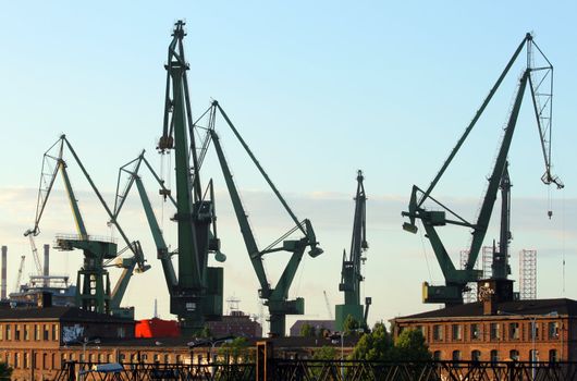 Harbour cranes silhouettes and industrial buildings at the historical shipyard in Gdansk, Poland
