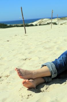 Woman's foot, on the sunny beach with the sea in background
