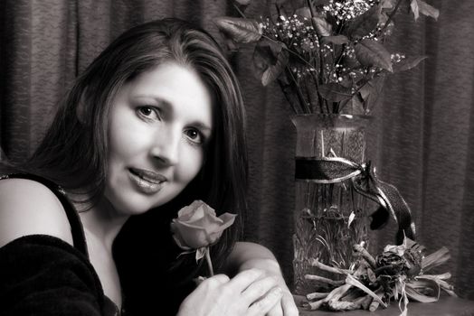 Brunette model holding a rose, looking at the camera