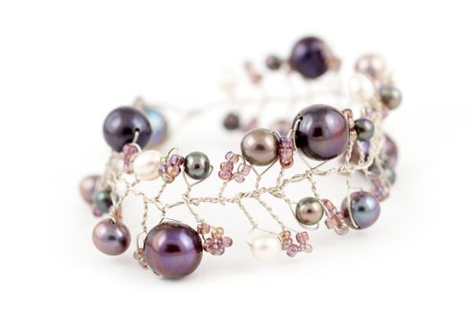 A bracelet made of silver and blue and purple Andaman sea pearls on a white on a background