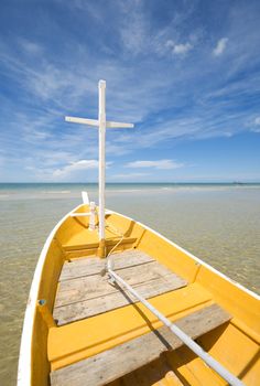 A white and yellow fishing boat on the ocean beach on a bright sunny day.