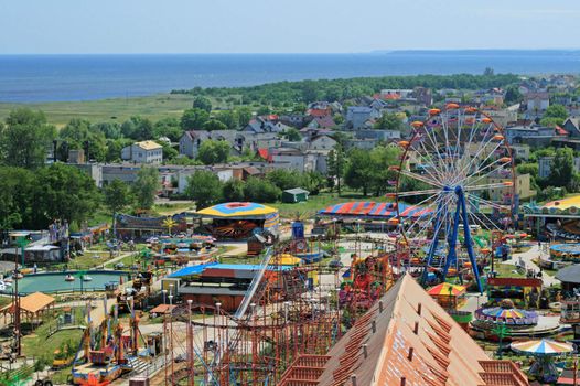Aerial view at the amusement park with ferris (devil's) big wheel and a bay in background
