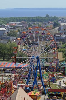 Aerial view at the amusement park with ferris (devil's) big wheel and a bay in background
