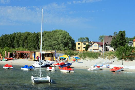 Sailing boats, pedalboats and other water fun stuff at the coast of the sea
