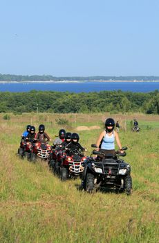 Group of young children riding quad / four-wheelers 4x4 on the meadow at the coastline
