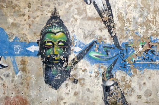 The head of Buddha painted graffiti style on city wall. 