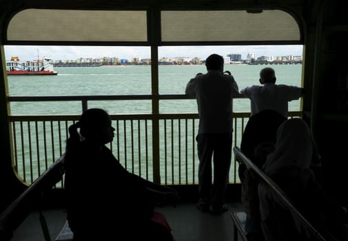 Silhouetted passengers on a ferry boat. 