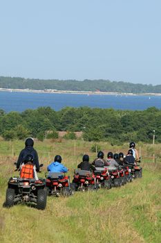 Group of young children riding quad / four-wheelers 4x4 on the meadow at the coastline
