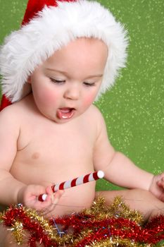 Christmas Baby playing with decorations on a green background