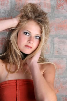 Beautiful female model with blue eyes against a brick wall