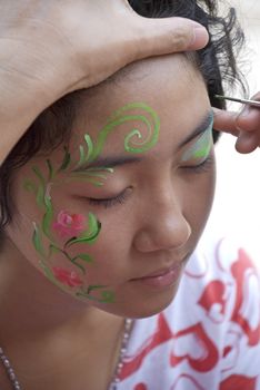 A young girl getting her face hand painted. 
