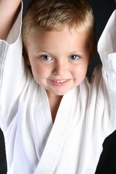 Young boy wearing his karate uniform on a black background
